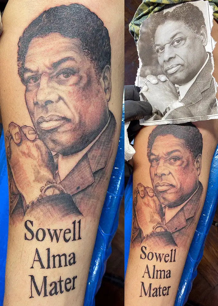 Masterful custom black-and-gray arm tattoo featuring a lifelike portrait of economist Thomas Sowell in contemplative pose, accompanied by 'Sowell Alma Mater' lettering and expert shading. A meaningful tribute honoring intellectual legacy.